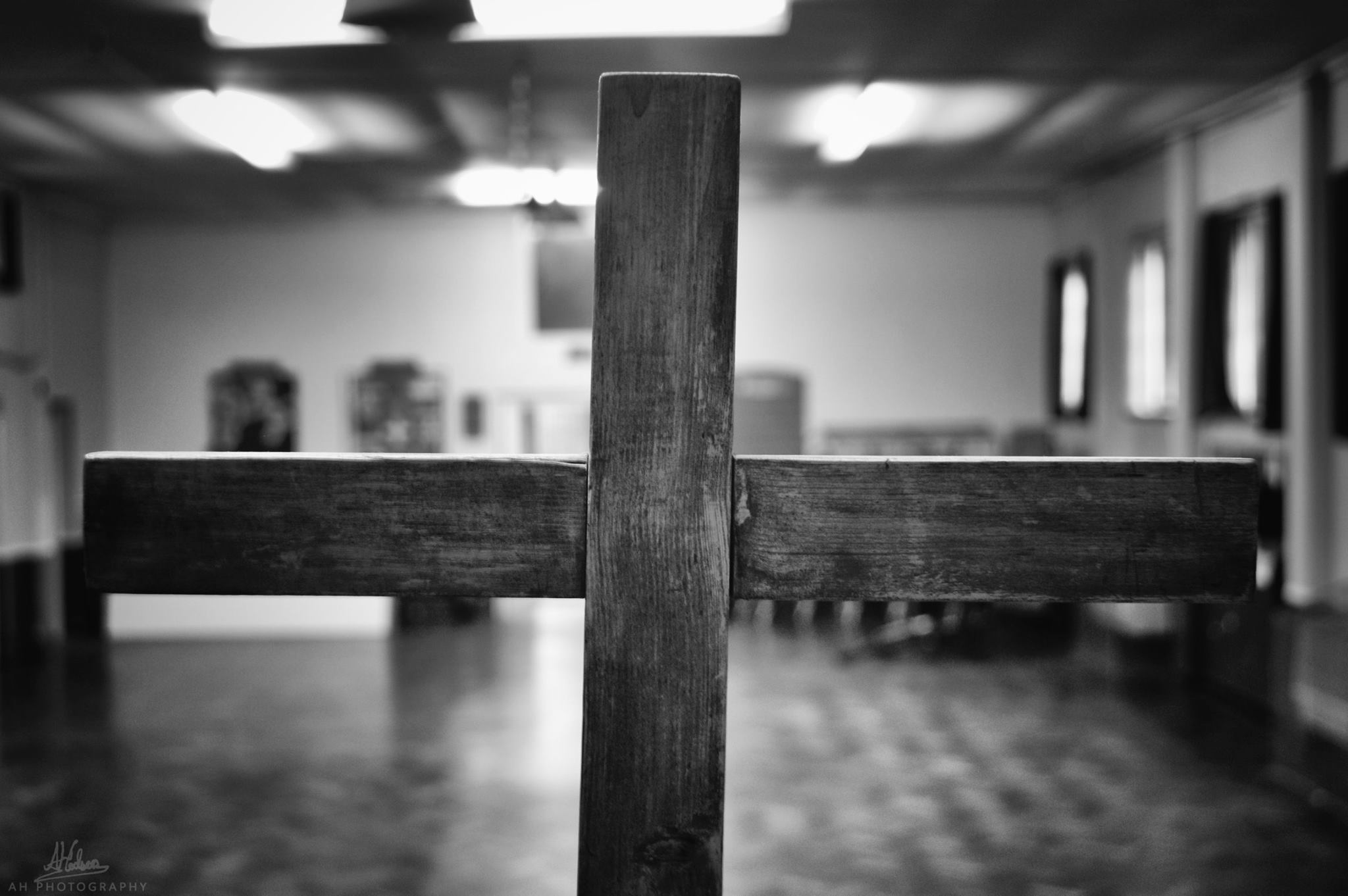 A black and white photo of a close up christain cross on a blurred background